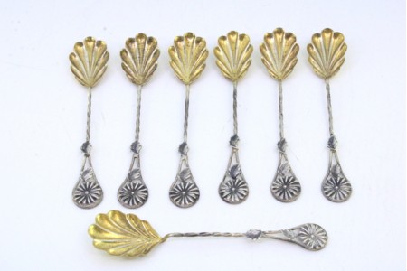 Conjunto de seis colheres de chá e pá de açúcar em prata dourada na concha em forma de flores.